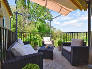 eine Terrasse mit Korbstühlen und einem Sonnenschirm in der Unterkunft Loubejac Garden Escape in Saint-Cernin-de-lʼHerm