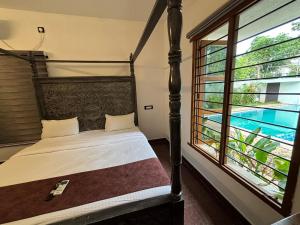a bedroom with a bed and a large window at Courtyard Castle Heritage Resort - Private Villa & Rooms in Pondicherry