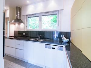 een witte keuken met een wastafel en een raam bij Oostduinkerke Forestside Villa in Oostduinkerke