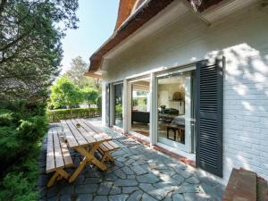 een houten bank op een patio naast een huis bij Oostduinkerke Forestside Villa in Oostduinkerke
