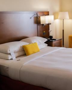 a large white bed with a yellow pillow on it at Marriott Venezuela Hotel Playa Grande in Playa Grande