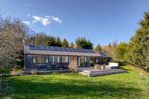 ein Haus mit Sonnenkollektoren auf dem Dach in der Unterkunft Oak Cottage and Hot Tub, Loch Tay in Lawers