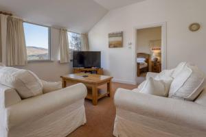 ein Wohnzimmer mit zwei Sofas und einem Fernseher in der Unterkunft Oak Cottage and Hot Tub, Loch Tay in Lawers
