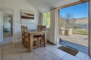 ein Esszimmer mit einem Tisch und einem großen Fenster in der Unterkunft Oak Cottage and Hot Tub, Loch Tay in Lawers