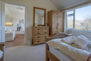ein Schlafzimmer mit einem Bett, einer Kommode und einem Spiegel in der Unterkunft Oak Cottage and Hot Tub, Loch Tay in Lawers
