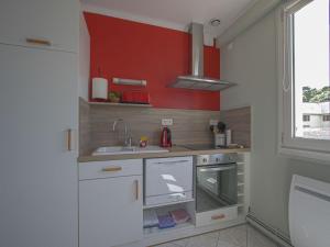 una cucina con lavandino e parete rossa di Apartment in Arromanches near Gold Beach ad Arromanches-les-Bains Altre 16 foto