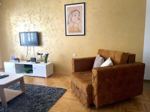 a living room with a brown couch and a tv at Apartman Bella in Sombor