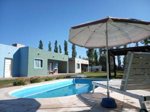 an umbrella and a chair next to a swimming pool at Cabañas Universo in San Rafael
