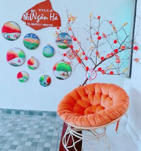 a orange chair in front of a wall with colorful plates at Villa Ngân Hà in Kon Rung (1)