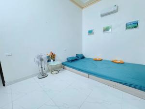 a bedroom with a blue bed and a fan at Villa Ngân Hà in Kon Rung (1)