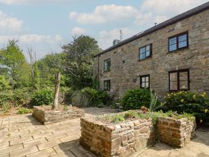 an old stone house with a garden in front of it at Mill House Barn in Penzance
