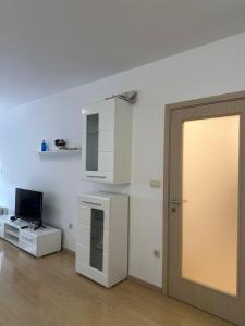 a white kitchen with a door and a television at Forte Mare Apartment in Podgorica