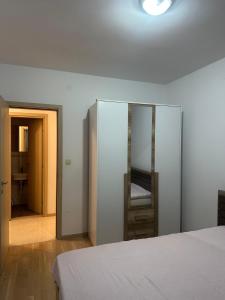 a white bedroom with a bed and a mirror at Forte Mare Apartment in Podgorica +3 photos