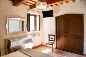 a bedroom with a bed and a tv and a chair at Genga Terme Retreat - 1 BR Apt with garden in Genga