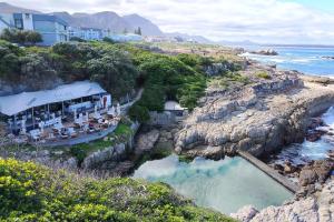 a restaurant on a cliff next to a body of water at Stylish Apartment in Hermanus in Hermanus
