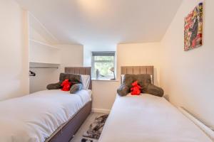 deux lits dans une pièce avec des animaux en peluche dessus dans l'établissement Rose Cottage - Crickhowell, à Crickhowell
