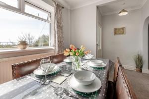un tavolo da pranzo con un vaso di fiori sopra di Ocean View Cottage - Burry Port a Burry Port Altre 13 foto