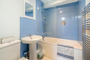 a blue bathroom with a sink and a tub and a toilet and a sink at Seacove in Saundersfoot +25 photos