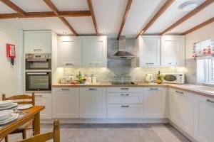 a kitchen with white cabinets and white appliances at Bryn Tirion Cottage in Llanfair Talhaiarn