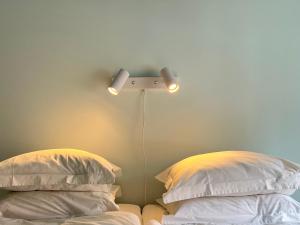 a bed with a light on the wall next to two pillows at Tiny house - in medieval Ystad in Ystad