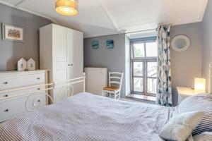 a bedroom with a bed and a dresser and a window at Lavender Cottage - Mumbles in The Mumbles