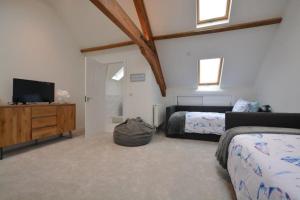 a bedroom with two beds and a flat screen tv at The Old Chapel in Saundersfoot