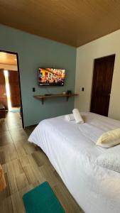 Un dormitorio con una cama blanca y un televisor de pantalla plana. en La Caracola, en Villa de Leyva