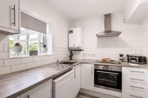 a white kitchen with a sink and a stove at Curlew Stays - Semi Detached Home - Pet Friendly in Thornton +6 photos