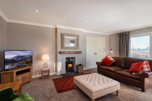 ein Wohnzimmer mit Sofa und Fernseher in der Unterkunft Balass Lodge near The Old Course St Andrews in Fife