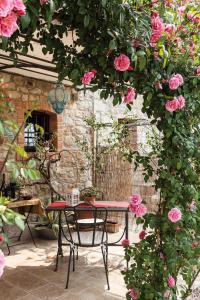 Ca' Piadera Wine Relais في Tarzo: طاولة وكراسي في حديقة بها ورد وردي