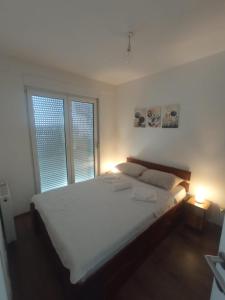 ein weißes Bett in einem Schlafzimmer mit zwei Fenstern in der Unterkunft ALEXiS in Modriča
