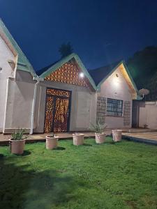 a house with a front door with potted plants in front at Kukis Place in Embu Airstrip-2 bedrooms with more beds in Embu