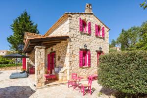 a stone house with pink windows and pink chairs at Villa Ariadne Aresti in Agios Leon