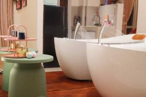 a bathroom with two white tubs on a wooden floor at Midas Seri Alam Luxury Dopamine Jacuzzi in Masai +24 photos