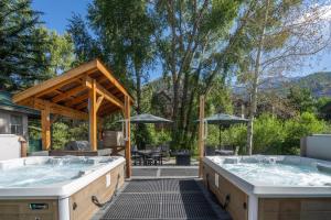 two hot tubs on a patio with a table at Mountainside Inn 201 by Alpine Lodging Telluride in Telluride