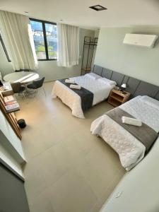 a bedroom with two beds and a desk at Campina Room Service in Campina Grande
