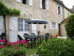 a table and chairs with an umbrella in a garden at Vintage Retreat in Montfaucon in Montfaucon