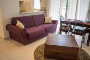 ein Wohnzimmer mit einem lila Sofa und einem Tisch in der Unterkunft Apartments Belmont Becici in Budva
