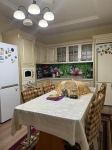 a kitchen with a white table with a table cloth on it at Mama Nuris guest house in Karakol +12 photos