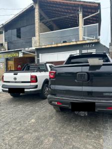 zwei Lastwagen stehen vor einem Geschäft in der Unterkunft CASA PISCINA CHURRASQUEIRA Wi-Fi BERTIOGA in Bertioga + 56 Fotos