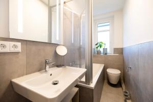 a bathroom with a sink and a toilet and a mirror at NORA Dresden Messe in Dresden