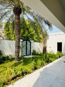 a palm tree in a yard with a gate at Neem Premium Villa in Al Jubayl