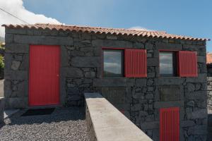 een stenen huis met rode deuren en ramen bij Casa do Sanguinho - Estúdio, Quinta do Rochão in Terra Alta