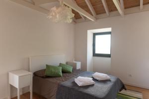 a bedroom with a bed with green pillows and a window at Casa do Sanguinho - Estúdio, Quinta do Rochão in Terra Alta