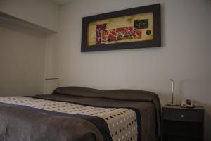 a bedroom with a bed and a painting on the wall at Hotel Amucan in Neuquén