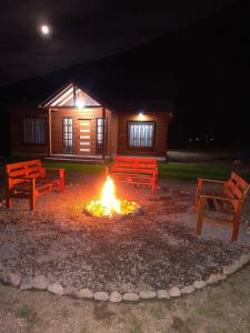 two benches sitting around a fire in front of a cabin at Cabaña en Parcela, Valle del Elqui in Diaguita