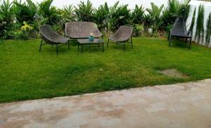 three chairs and a table in the grass at Magnifique Appartement pieds sur mer, 2 chambres in Sidi Rahal