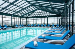 a large swimming pool with blue chairs in a building at Le Ru'Beach - T2 avec piscine in Trouville-sur-Mer