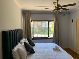 a bedroom with a bed with a ceiling fan and a window at Palm Haven on Sarnia in Durban