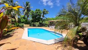 una piscina en un complejo con palmeras en Casa Lyrio - Itacimirim, en Camassari